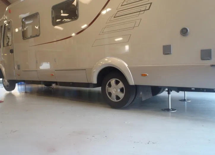 Autocamper løftet på hydrauliske støtteben i værkstedet