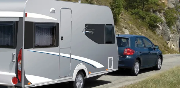 Sølvgrå campingvogn på slæb ad en bjergvej